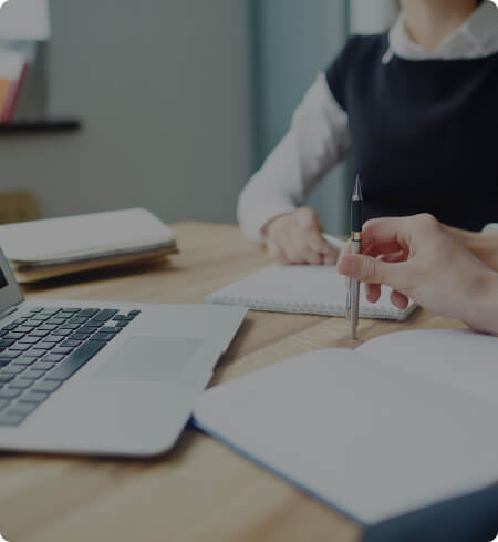 Serviços Claro Imobiliária Pessoas ao redor de um notebook e cadernos, com uma caneta na mão
